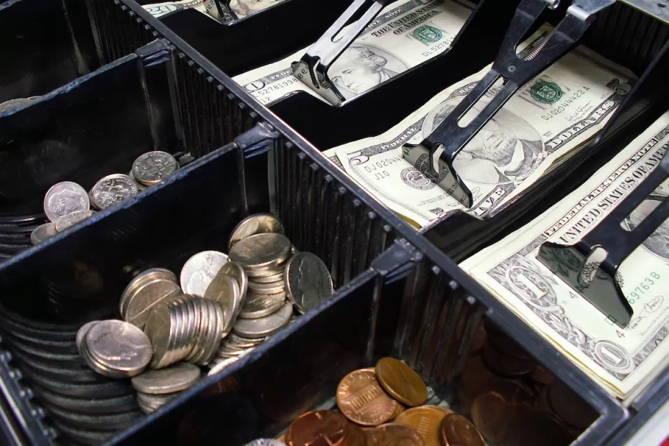 Close-up of cash drawer with various dollar bills and coins.